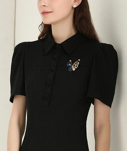 Détail d'une élégante broche papillon avec strass bleus sur une robe noire ajustée