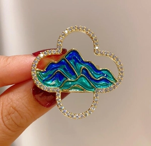 Macro view showing a four-leaf clover brooch with mountain enamel and sparkling zircons