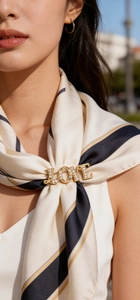 Golden LOVE brooch with white crystals pinned on a striped scarf shown on a model