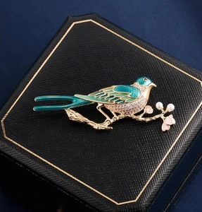 Detail of vintage magpie brooch with blue enamel wings and pearls on a jewelry box