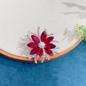 Elegant flower brooch with red crystal petals, central pearl, and sparkling diamond accents