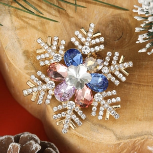 Detailed close-up of a snowflake brooch with colorful gems on a rustic wooden background