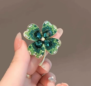 Gros plan détaillé d'une broche trèfle à quatre feuilles avec cristaux verts brillants