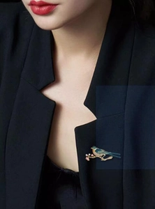 Detailed view of an enamel magpie bird brooch pinned on a black suit jacket lapel