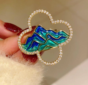 Macro shot of mountain pattern brooch with blue-green enamel and white zircon inlay
