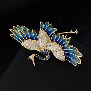 Spilla elegante a forma di gru con smalto blu e finitura dorata su fondo scuro