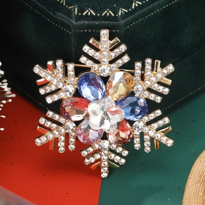 Macro shot of snowflake brooch with colorful rhinestones and gold-tone finish details