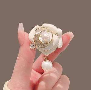 Élégante broche camélia en perles avec bords dorés et détail de lune en cristal