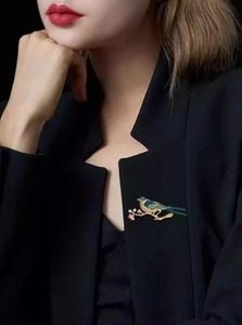 Detailed enamel magpie brooch with blue-green gradient on a black suit lapel