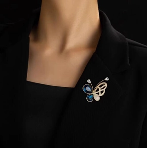 Broche papillon vintage française avec pierres bleu foncé sur le revers d'un costume noir