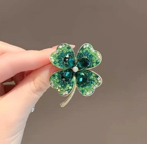 Détail d'une broche trèfle à quatre feuilles avec strass verts et métal doré brillant