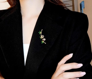 Detailed view of a panda brooch with green enamel bamboo on a black suit lapel