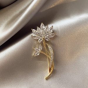 Broche lotus dorée avec pétales en zircon marquise sur un fond élégant en satin champagne