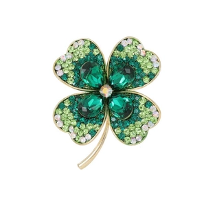 Détail d'une broche trèfle dorée ornée de strass verts et de cristaux scintillants
