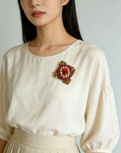 Dettaglio di spilla vintage in stile palazzo con cristallo rosso e perle su maglione