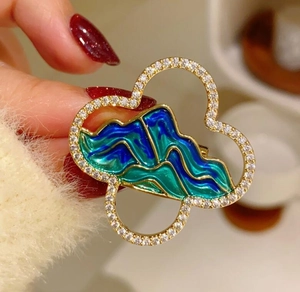 Close-up of Chinese style landscape brooch with sparkling diamonds and gold enamel finish