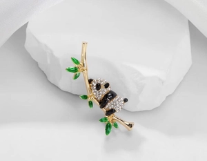 Detailed view of gold panda brooch with sparkling white crystals and green enamel bamboo branch