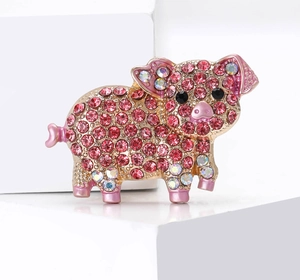 Macro shot of pink rhinestone encrusted pig brooch with sparkling gold-tone metal base