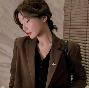 Detailed view of a golden heart brooch with angel wings on a brown suit lapel