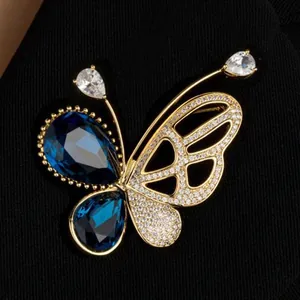 Broche papillon dorée avec pierres précieuses bleues et cristaux sur un revers de veste