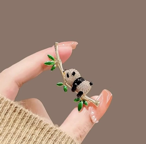 Close-up of a panda climbing bamboo brooch with sparkling rhinestones and green enamel details