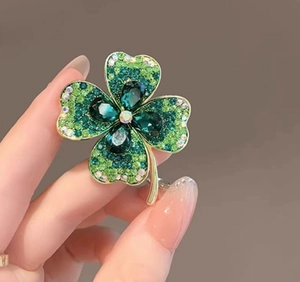 Vue détaillée de la broche trèfle à quatre feuilles dorée avec cristaux verts pavés
