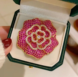 Détail de la broche camélia en or rose sertie de zircons dans un écrin en velours