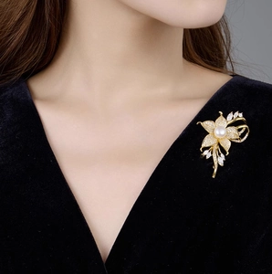 Detailansicht einer eleganten Blumenbrosche mit Perlen und Zirkonia auf einem Anzug