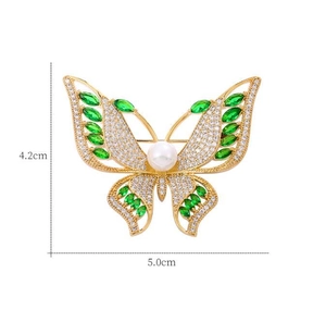 Vue détaillée de la broche papillon en or avec cristaux verts et accents de perles blanches