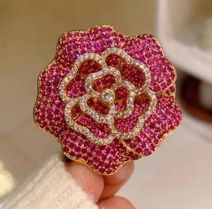 Détail macro d'une broche camélia rose rouge vintage français avec pavage de diamants