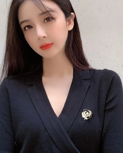 Close-up of a white camellia brooch with gold edges pinned on a black knit top