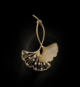 Nahaufnahme der goldenen Ginkgo-Brosche mit funkelnden Kristallen auf schwarzem Samt