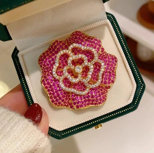 Vue macro de la broche fleur camélia 3D avec strass roses en boîte de velours vert