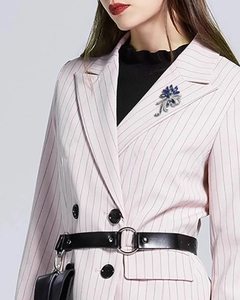 Gros plan d'une broche fleur élégante avec cristaux bleus sur un blazer rose