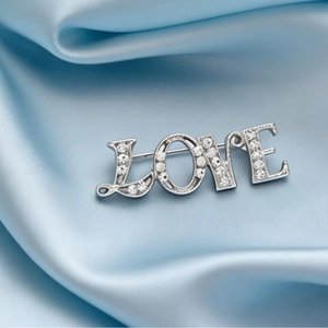Elegant LOVE letter brooch in silver alloy with rhinestones on light blue satin fabric