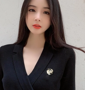 Detailed view of a white camellia flower brooch pinned on a black suit lapel