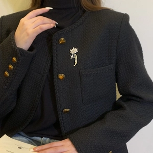 Élégante broche lotus bicolore avec pétales en zircone sur un blazer en tweed noir