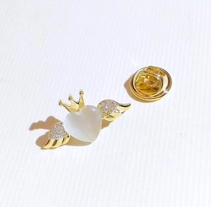 Detailed macro view of the gold-plated crown heart brooch with white cat eye stone