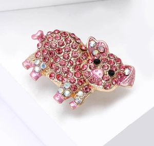 Detailed view of pink crystal pavé pig brooch with gold base and colorful rhinestones