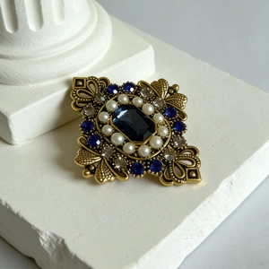 Spilla vintage dorata con pietra blu rettangolare e perle su colonna di pietra