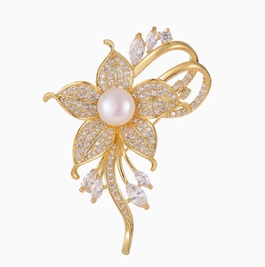 Detailansicht der goldenen Blumenbrosche mit Zirkonia-Blütenblättern und zentraler Perle