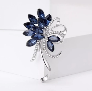 Détail d'une broche bauhinia avec cristaux marquise bleus et pompons en métal argenté