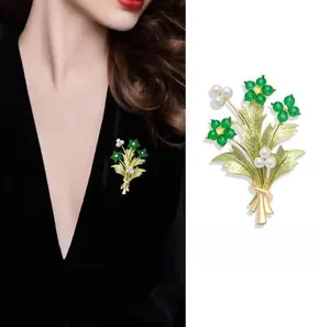 Dettaglio della spilla a bouquet con perline verdi, perle bianche e lega dorata