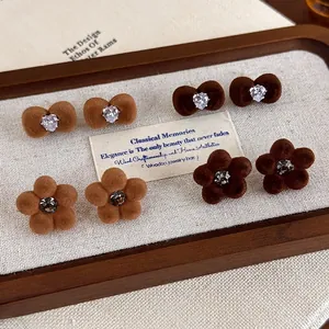 Brown flocked bow and flower stud earring set with zircons on a wooden display