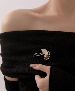 Detailansicht der Ginkgoblatt-Brosche in Gold mit Kristallen auf schwarzer Strickware
