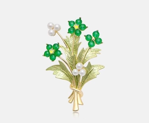 Dettaglio spilla a bouquet con fiori in pietra verde e perle su base in metallo dorato