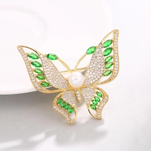 Broche papillon de luxe avec pierres vertes et perle blanche sur monture dorée