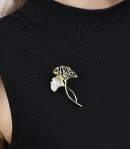 Detail einer luxuriösen Gold-Ginkgo-Brosche mit Kristallen auf schwarzem Pullover