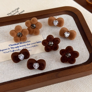 Detail of brown flocked flower and bow earrings with rhinestones on a wooden tray