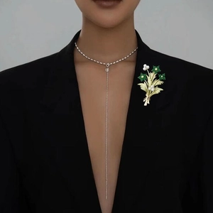 Spilla bouquet elegante con cristalli verdi e perle bianche su abito nero formale